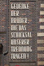 Inscription Commemorate the brothers who bear the fate of our separation on the brick facade of the