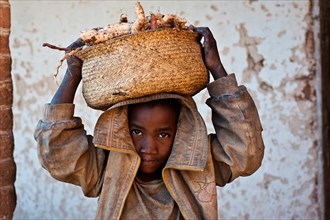 Boy carrying on his head a basket full of sweet potatoes, Ambositra, Madagascar, He belongs to the