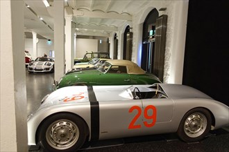 A silver Porsche racing car with starting number 29 is parked among other classic cars, AUTOMUSEUM