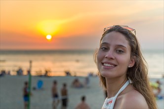 Young woman looking at camera at sunset on the beach