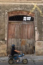 Fat woman on a moped in front of an old warehouse, rural scene in Victoria, Duck, Argentina, South