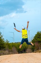 Worker jumping and raising arms in a path in a green energy park