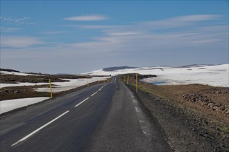 Road leads through barren mountain landscape with snow and ice, Seydisfjoerdur, Fjaroarheioi,