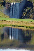 Water masses plunge vertically into the depths, reflection in the water, green landscape,