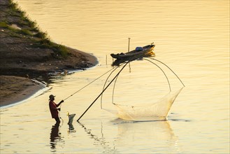 Fisherman with a sinking net at sunset on the Mekong, Luang Prabang, Laos, Asia