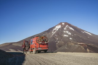 Young woman and her campervan in front of the Lonquimay volcano, Lonquimay volcano, Malalcahuello