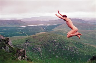 Naked man jumping in front of mountain scenery, Connemara National Park, Republic of Ireland, 20