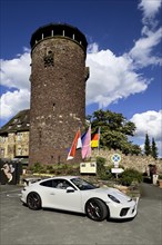Porsche 911 GT3 stands in front of 13th century castle today Burghotel Trendelburg with castle