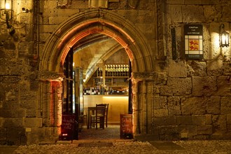 Illuminated entrance of a restaurant with warm light and vaulted architecture at night, night shot,