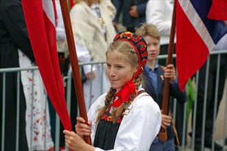 Young girl in old traditional costume walking on the streets waving flags, folklore, bank holidays