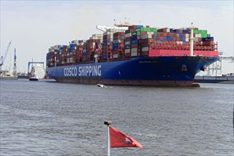 Container freighter of the China Ocean Shipping Company COSCO leaving the harbour on a sunny day at