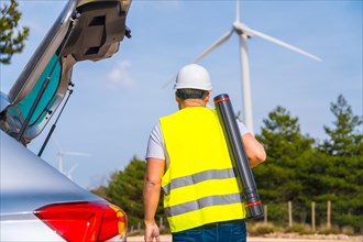 Rear view of a male worker with drawing tube walking along a wind energy park