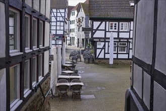 Passageway between half-timbered houses with outdoor areas of catering establishments in the old