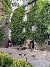 Castle courtyard with green overgrown building of 13th century castle today Burghotel Trendelburg,