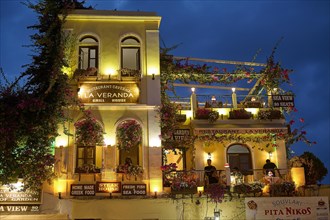 A charmingly illuminated restaurant with flowers on the facade in the evening, night shot, Rhodes