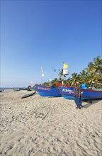 Indian fisherman, 42 years old, and colourful fishing boats at Marari Beach or beach, Mararikulam,