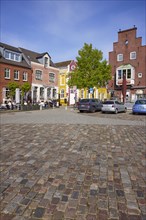 Restaurant and houses with colourful facades and a street of cobblestones in the harbour of Husum,