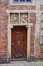 Relief in the lintel and old wooden door of a house in Boettcherstrasse in Bremen, Hanseatic city,