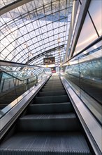 Escalator leads into a modern station concourse with an impressive glass roof, Berlin, Germany,