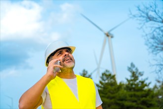 Worker wearing safety gear talking to the mobile phone in a wind energy park