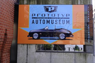 An advertising banner for the prototype car museum with an image of a classic car against an orange