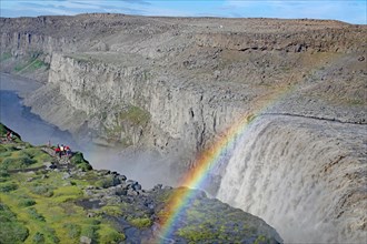 Group of people in front of waterfall, rainbow, barren landscape, Dettifoss, vatnajoekull National
