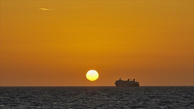 A ferry sails in front of a bright orange sky at sunset on the sea, dusk, sunset, Rhodes,