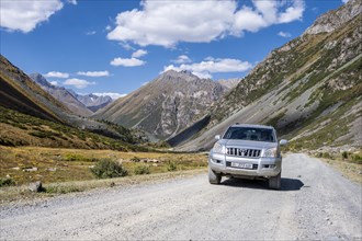 Off-road car on gravel road in the mountains in the Tien Shan, mountain valley, Issyk Kul,