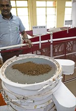 Indian man, 40 years old, showing an automatic tea strainer at the Munnar Tea Museum, Munnar,
