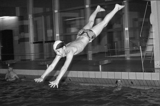 Boy jumps from three-metre board, head dive, indoor swimming pool, Bamberg, Upper Franconia,