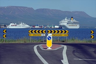 Street with distances, behind it the sea with two cruise ships, Akureyri, Iceland, Europe
