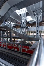 Modern station concourse with glass details and a red train in the background, Berlin, Berlin