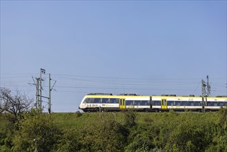 Regional train of the mobility brand bwegt unterwegs, railway embankment and overhead lines,