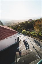 Two people walking down a sunlit street. Madeira, Portugal, Europe