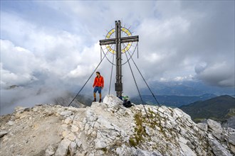Mountaineer on the summit of the Grosser Kinigat with summit cross, Carnic Main Ridge, Carnic High