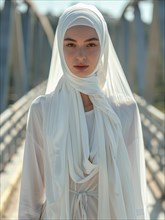 Serene woman in a white hijab on a bridge, in natural daylight, AI generated