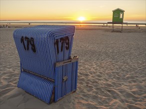 Sunset on the beach with a blue beach chair and a peaceful golden sky, beautiful sunset on the