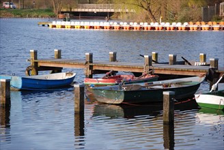 Small boats are moored on wooden jetties, calm water, in spring and under a blue sky, rowing boats