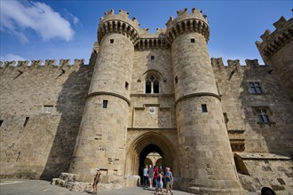 Super wide angle shot, travellers standing in front of an imposing crenellated old castle facade,