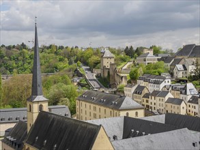 View of a city with a large church and many historic buildings, embedded in a green hilly landscape