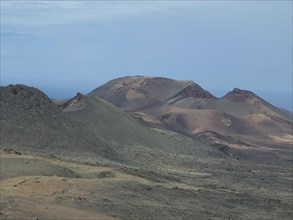 Rocky volcanic landscape with hills and a view of the sea in the background, barren landscape with