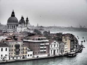 Romantic, foggy city view along the canal of Venice, church towers and historic buildings along a