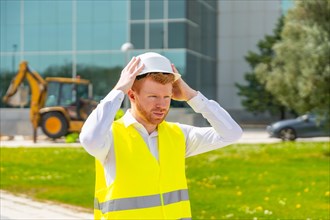 Architect wearing reflective waistcoat adjusting her safety hard hat in a construction site