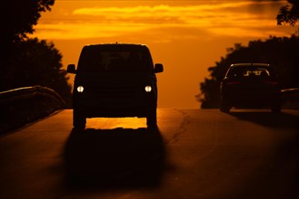 Two cars driving along a country road in Frankfurt am Main at sunrise, Frankfurt am Main, Hesse,