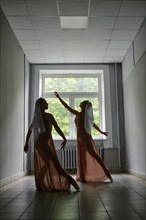 Silhouette of two ballerinas repeat dance steps in the corridor