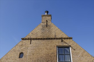 Brick house facade with chimney in front of a clear blue sky, minimalist look, historic houses in a