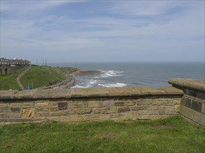 A tranquil coastal scene with a stone wall in the foreground and the sea in the background. Waves