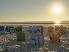 Several colourful beach chairs on the sandy beach by the sea as the sun sets, sunset on a quiet