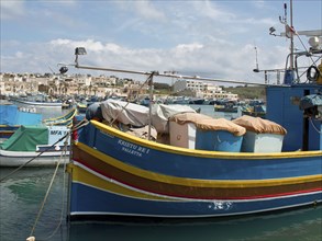 A colourful fishing boat in the harbour under a cloudy sky in a coastal town, many colourful