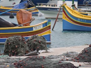 Fishing boats and nets are spread out on a pier in the harbour, many colourful fishing boats in a